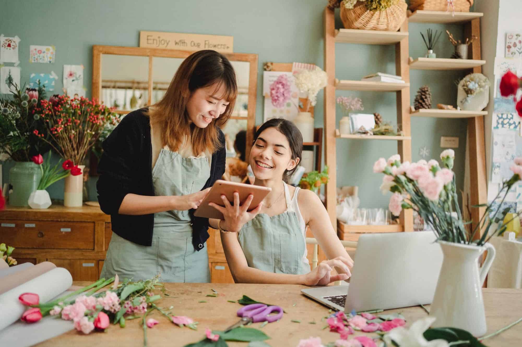 Two women looking at tablet in florist store